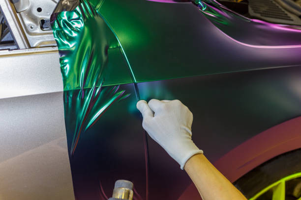 Installer smoothing a color-shift vinyl wrap onto a car fender in Magnolia, Texas